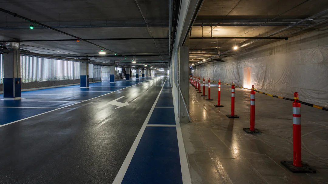 Finished parkade zone beside an isolated coating phase with temporary barriers