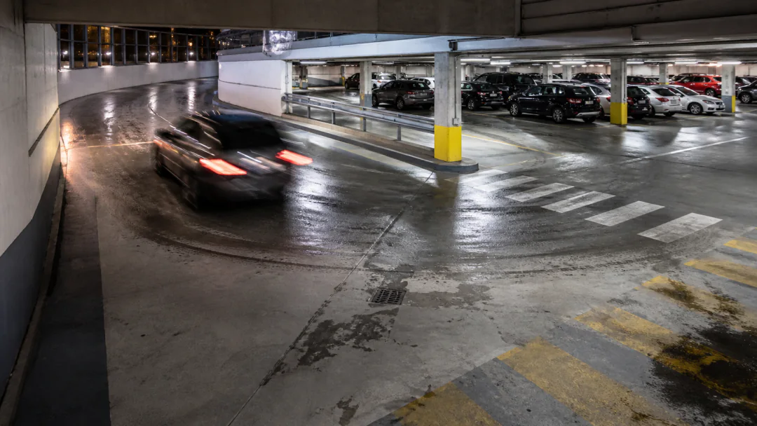 Active commercial parkade showing traffic, ramp, drainage and wet-weather floor exposure